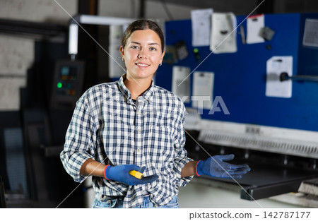 Woman posing with tape measure in metallurgical workshop Woman posing with tape measure in metallurgical workshop 142787177