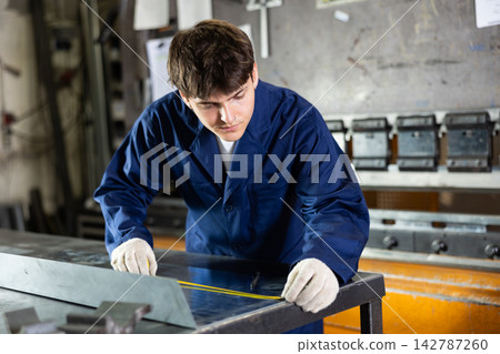 Young technician measuring steel sheet in metalworking workshop Young technician measuring steel sheet in metalworking workshop 142787260