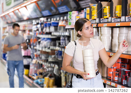 Young girl choosing painter tape in local construction hypermarket Young girl choosing painter tape in local construction hypermarket 142787262