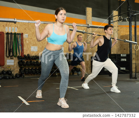 Sporty young girl doing exercises with barbell in gym 142787332