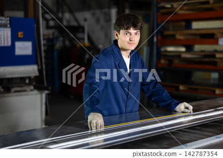 Positive young worker marking steel sheet in metal workshop 142787354