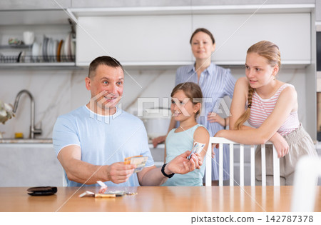 Joyful daughters surrounded dad in kitchen and asked for money Joyful daughters surrounded dad in kitchen and asked for money 142787378