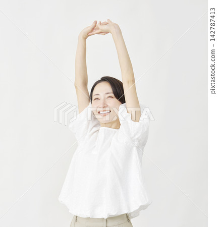 A middle-aged woman stretching against a white background. A middle-aged woman stretching against a white background. 142787413
