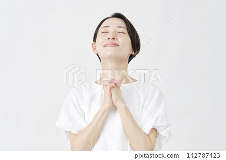 一位中年婦女在白色背景前祈禱。 142787423