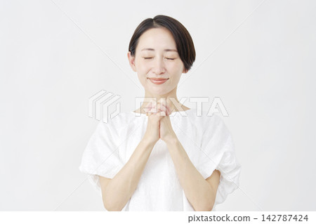 一位中年婦女在白色背景前祈禱。 142787424
