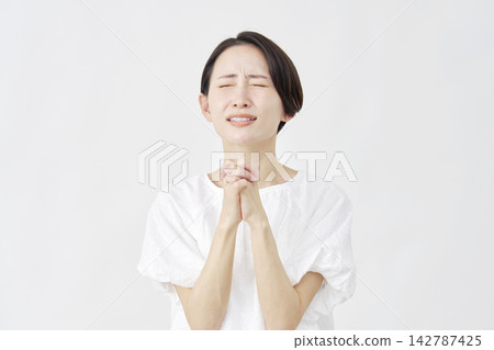 A middle-aged woman pleading against a white background. 142787425
