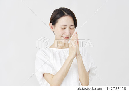 A middle-aged woman praying against a white background. A middle-aged woman praying against a white background. 142787428