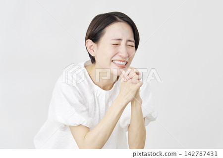 一位中年婦女在白色背景前懇求。 142787431