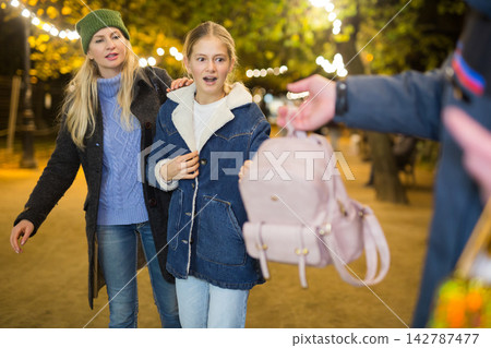 Man stealing girl's backpack Man stealing girl's backpack 142787477