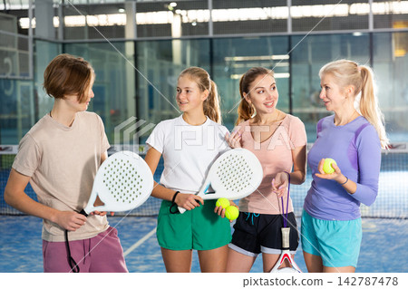 Four padel players standing in court and having conversation Four padel players standing in court and having conversation 142787478