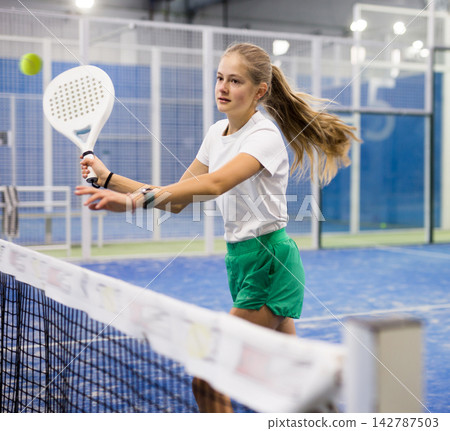 Young girl with racquet playing padel Young girl with racquet playing padel 142787503