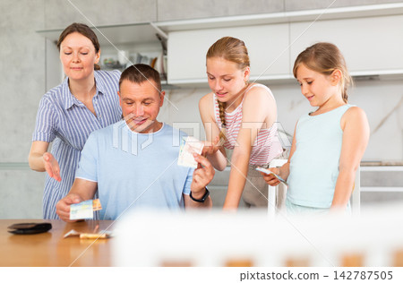 Man gives his smiling wife and daughter money for ladie' nice little things, trinkets Man gives his smiling wife and daughter money for ladie' nice little things, trinkets 142787505