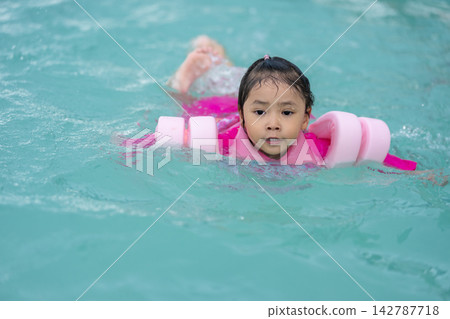 preschool child girl playing and swimming with floaties in pool water preschool child girl playing and swimming with floaties in pool water 142787718