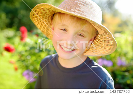 Portrait of preteen boy wearing stray hat on the domestic garden at summer sunny day. Summertime holidays for kids in the village Portrait of preteen boy wearing stray hat on the domestic garden at summer sunny day. Summertime holidays for kids in the village 142787793