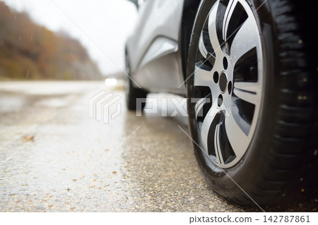Close-up of car tires: low-angle view, roadside in a mountain valley, autumn day. 142787861