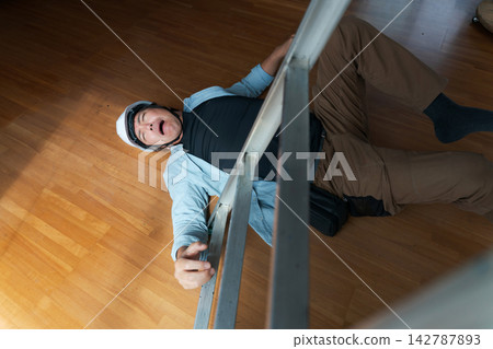 一名男工人從梯子上摔了下來。 一名男工人從梯子上摔了下來。 142787893