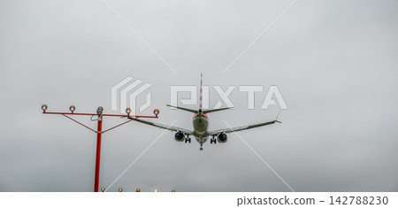 Commercial aircraft on final approach framed by security barbed wire fencing Commercial aircraft on final approach framed by security barbed wire fencing 142788230