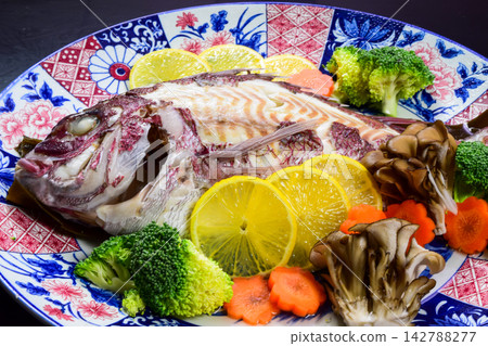 一道奢華的魚菜餚,選用一整條鯛魚,保留了魚頭和魚尾,搭配色彩繽紛的蔬菜。 一道奢華的魚菜餚,選用一整條鯛魚,保留了魚頭和魚尾,搭配色彩繽紛的蔬菜。 142788277