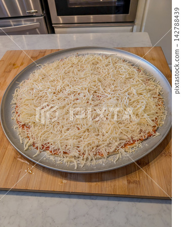 Unbaked plain cheese pizza on metal baking pan Unbaked plain cheese pizza on metal baking pan 142788439
