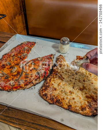 Thin crust pizza slices on baking tray with shaker Thin crust pizza slices on baking tray with shaker 142788466