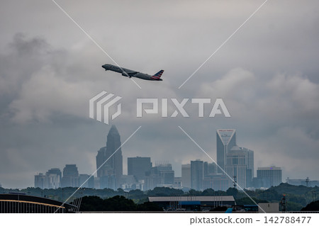 Passenger airplane flying high above Charlotte skyline Passenger airplane flying high above Charlotte skyline 142788477