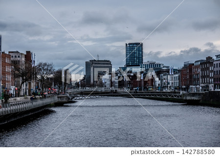 Dublin Ireland Urban Street and River Liffey Views with Bridges Traffic Buses and Historic City Architecture Under Cloudy Sky Dublin Ireland Urban Street and River Liffey Views with Bridges Traffic Buses and Historic City Architecture Under Cloudy Sky 142788580
