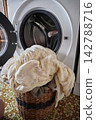 Laundry Routine: Washing a Pile of Clothes in Front of an Open Washing Machine Door 142788716