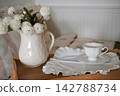 Elegant Teacup and Floral Arrangement on a Wooden Tray in a Cozy Bedroom Setting 142788734