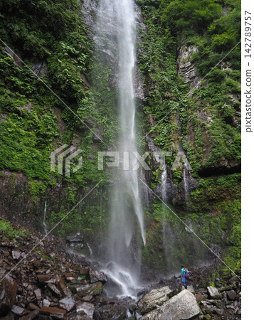 Kirigataki Falls, with a drop of approximately 60 meters, and people looking up at the waterfall. Kirigataki Falls, with a drop of approximately 60 meters, and people looking up at the waterfall. 142789757