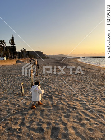 A small child walking on the beach at dusk A small child walking on the beach at dusk 142790173