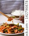 Eating stir fried asparagus with kimchi cabbage, pork and cooked rice by chopsticks, Korean style 142790878