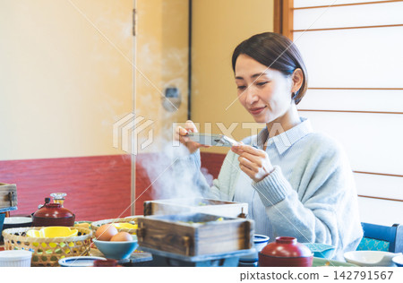 一位女士正開心地用智慧型手機拍攝她的餐點照片。 一位女士正開心地用智慧型手機拍攝她的餐點照片。 142791567