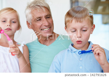 Grandfather, kids and bubbles with bonding in home for child development with retirement. Grandpa, grandkids and fun for relax with relationship with smile for happiness, positivity and happy family Grandfather, kids and bubbles with bonding in home for child development with retirement. Grandpa, grandkids and fun for relax with relationship with smile for happiness, positivity and happy family 142791826