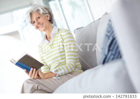Senior woman, book and portrait on sofa in home with smile, literature or relax with poetry in retirement. Mature person, reading and happy with mystery, fantasy or knowledge on lounge couch in house Senior woman, book and portrait on sofa in home with smile, literature or relax with poetry in retirement. Mature person, reading and happy with mystery, fantasy or knowledge on lounge couch in house 142791833
