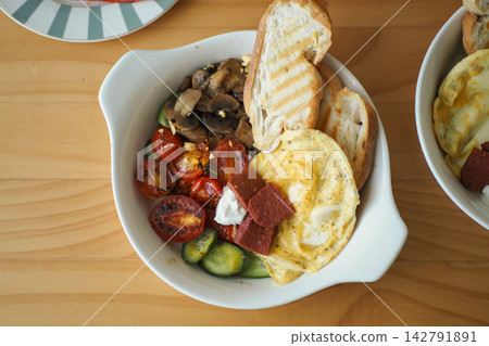 Delicious breakfast bowl with eggs, vegetables, and toasted bread Delicious breakfast bowl with eggs, vegetables, and toasted bread 142791891
