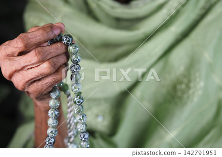 an elderly person holding a set of Islamic prayer beads an elderly person holding a set of Islamic prayer beads 142791951