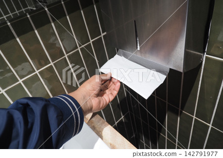 Hand reaches for paper towel in a public restroom setting 142791977