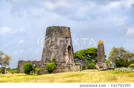 Old stone windmill tower and chimney ruins of the historic Habitation Roussel Trianon sugar plantation in Marie-Galante, Guadeloupe, Caribbean France Old stone windmill tower and chimney ruins of the historic Habitation Roussel Trianon sugar plantation in Marie-Galante, Guadeloupe, Caribbean France 142793395