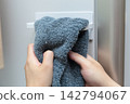 A housewife wipes her hands on the towel rack in the refrigerator. 142794067