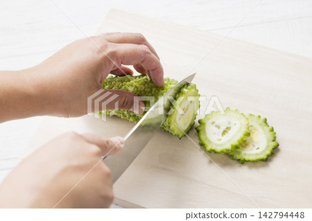 用刀將苦瓜切成片的手 用刀將苦瓜切成片的手 142794448