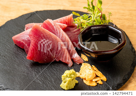 精美的鮪魚刺身盛放在黑色石盤中。 142794471