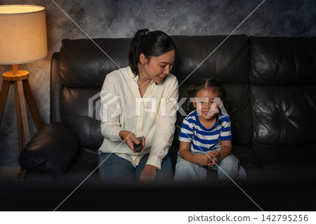 funny mother and daughter laughing while watching comedy film on tv in the living room at night funny mother and daughter laughing while watching comedy film on tv in the living room at night 142795256