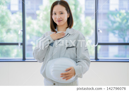 一位身著工作服的年輕女子,一隻手放在胸前──肖像 一位身著工作服的年輕女子,一隻手放在胸前──肖像 142796076