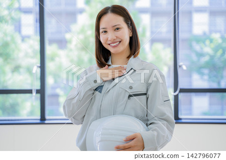 一位身著工作服的年輕女子,一隻手放在胸前──肖像 一位身著工作服的年輕女子,一隻手放在胸前──肖像 142796077