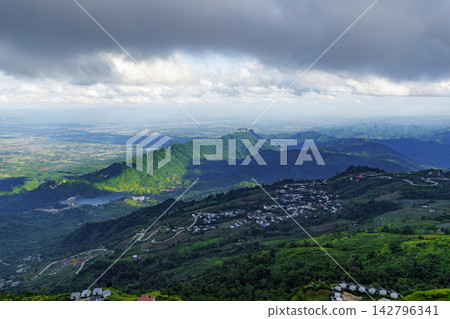 Mountain landscape with a road and houses under impending rain, photographed from a high angle. Mountain landscape with a road and houses under impending rain, photographed from a high angle. 142796341