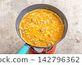 Fresh and appetizing Thai-style omelet cooking in a frying pan. 142796362