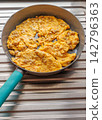 Fresh and appetizing Thai-style omelet cooking in a frying pan. 142796363