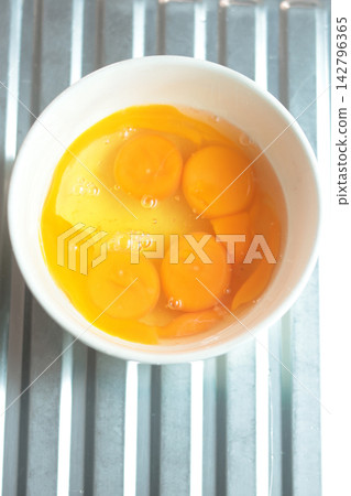 Cracking a raw egg into a bowl, preparing to fry an egg. 142796365