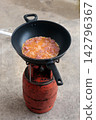 Thai-style omelet with fermented pork sausage (naem) cooking in a hot frying pan. 142796367