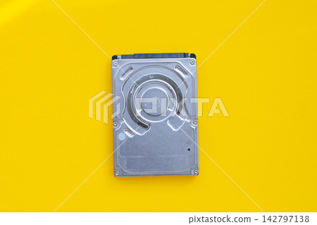 Top view of a metallic internal computer hard drive isolated on a bright yellow background. Top view of a metallic internal computer hard drive isolated on a bright yellow background. 142797138